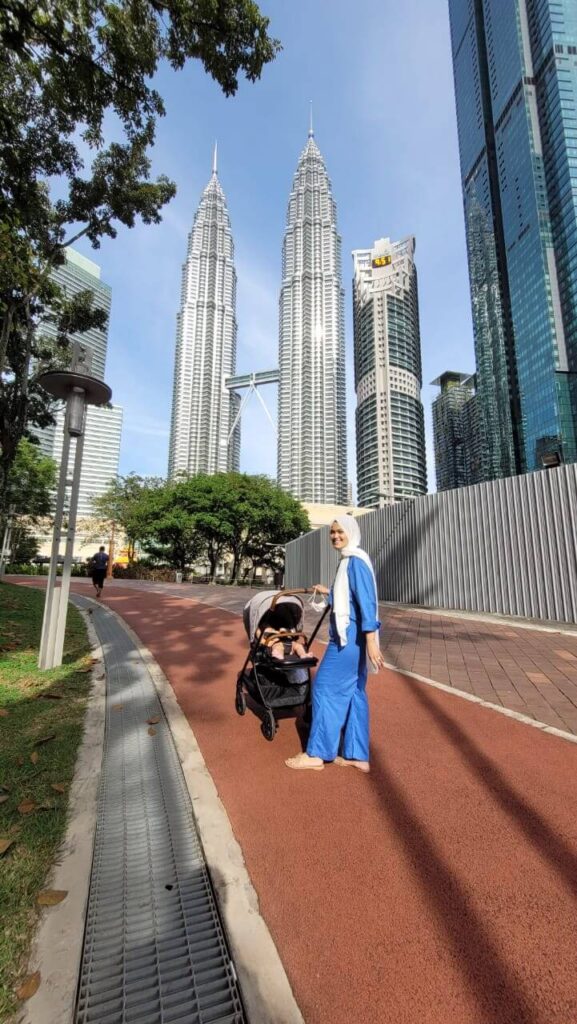 woman walking along the jogging path at klcc park with her baby in the stroller 