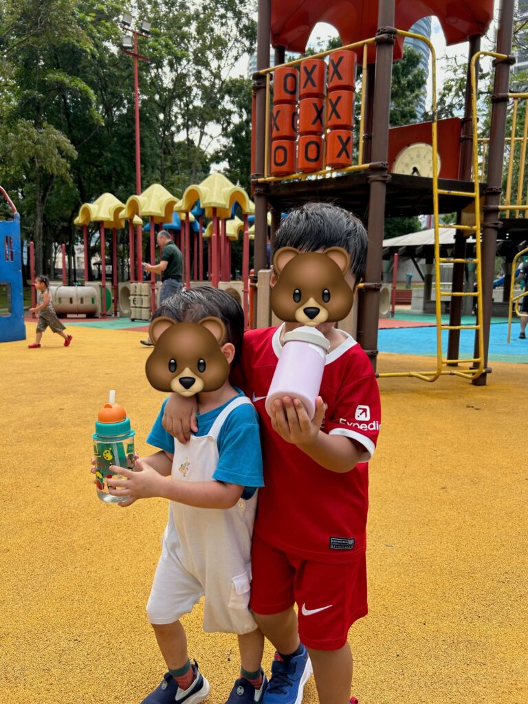 two young boys holding their bottles at the KLCC Park playground 