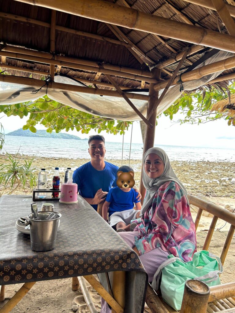 A couple with their son sitting at a dining table having dinner by the Patong beach in Phuket 