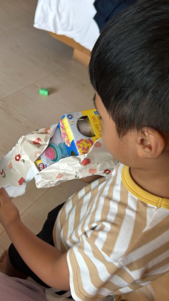 A toddler boy opening up a wrapped gift 