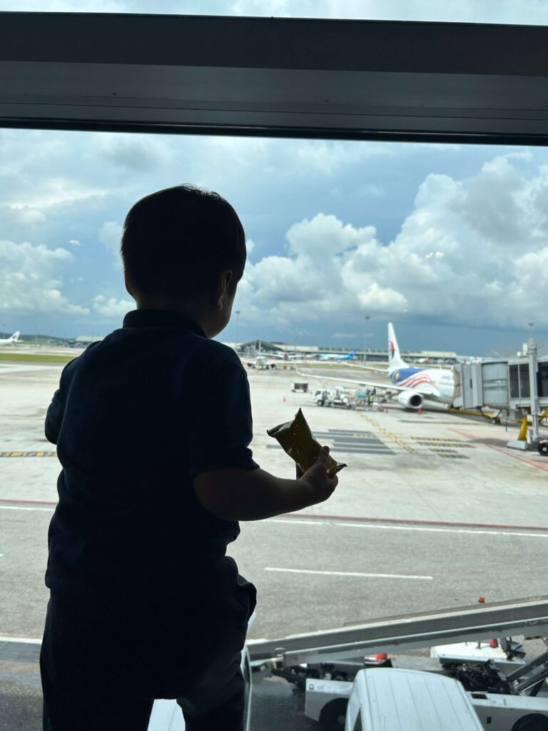 A toddler boy overlooking the airport with planes 