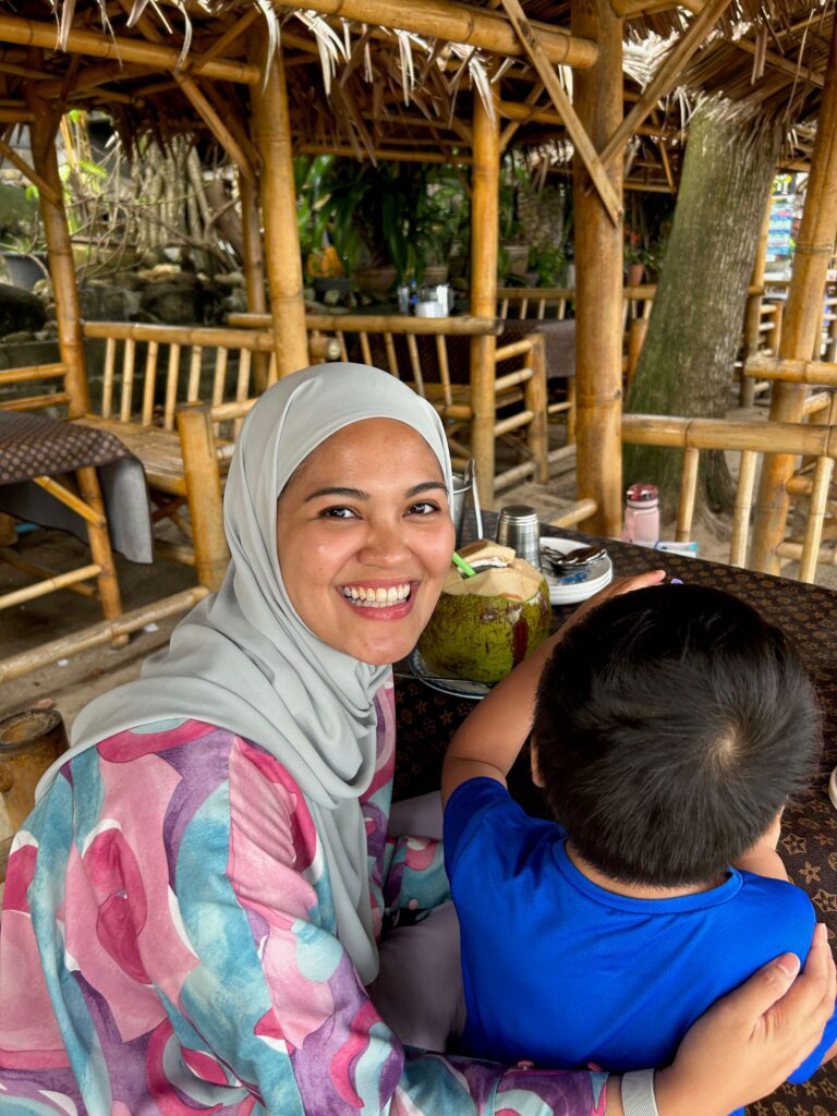 A woman smiling sitting next to her son during dinner at a beach side restaurant in Phuket 