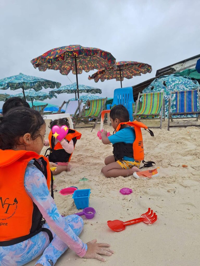 Kids playing with sand and toys at the beach in Khai Islands Phuket, they are wearing swimming clothes with orange vests 