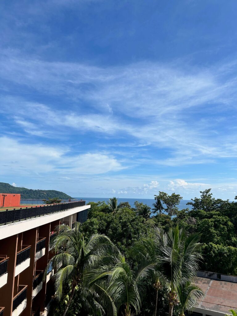 View overlooking the sea by Kata Beach in Phuket from Novotel Phuket Kata Avista Hotel with blue sky and lots of trees 